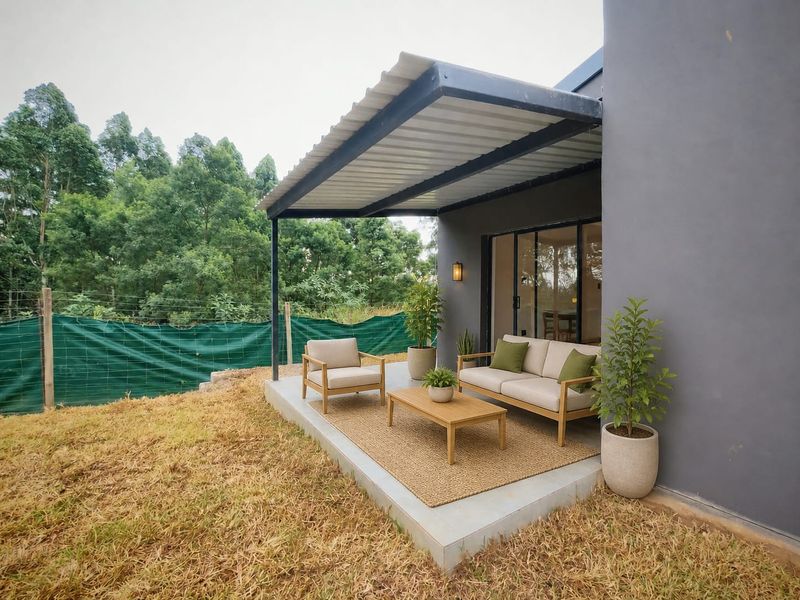 A covered concrete patio area featuring a modern metal roof structure and sliding glass door access to the interior living space.