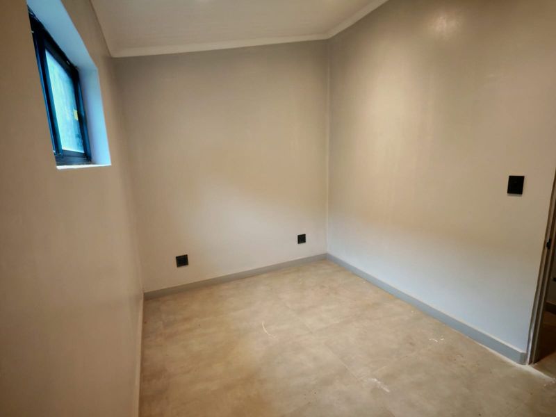 A clean, empty bedroom featuring neutral wall paint, tiled flooring, and a modern black-framed window, ready for personalization.