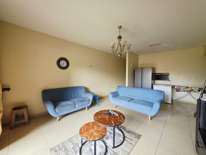 Open plan living area featuring tiled flooring and a ceiling chandelier, showing visible signs of ceiling water damage.