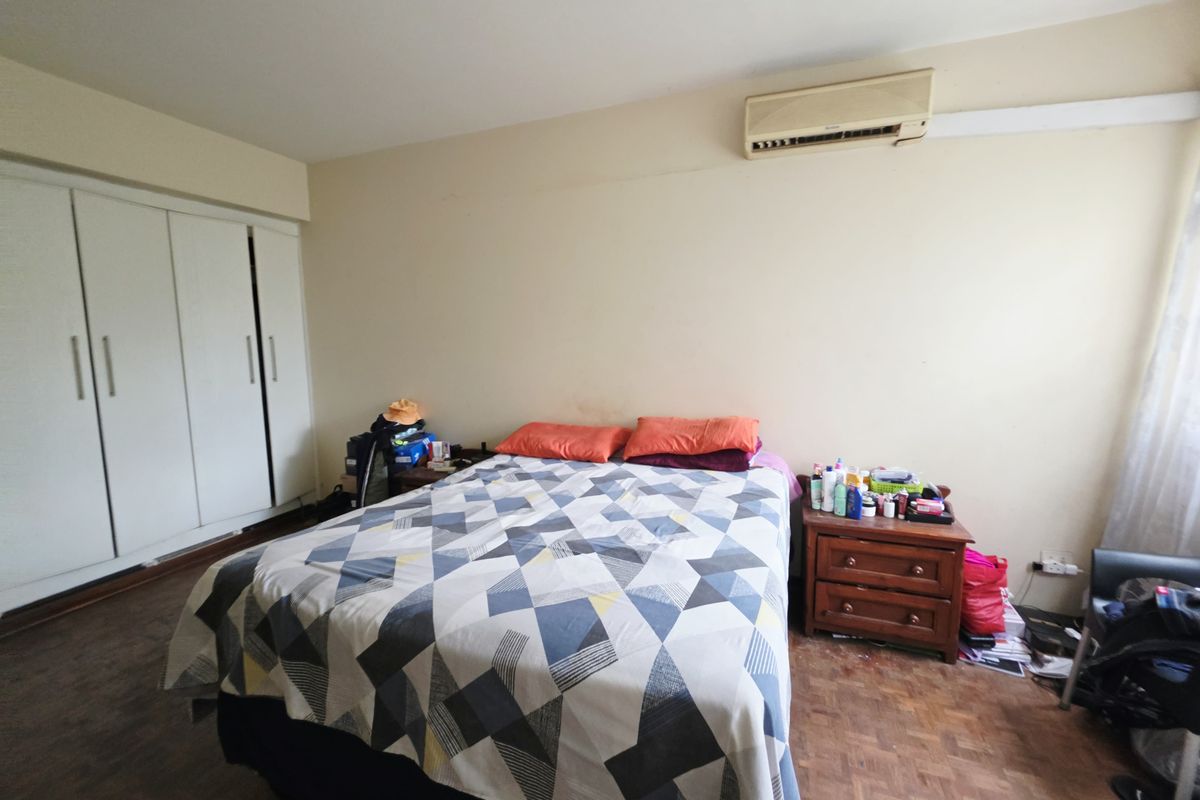 A bedroom featuring parquet flooring, a built-in wardrobe, and a wall-mounted air conditioning unit.