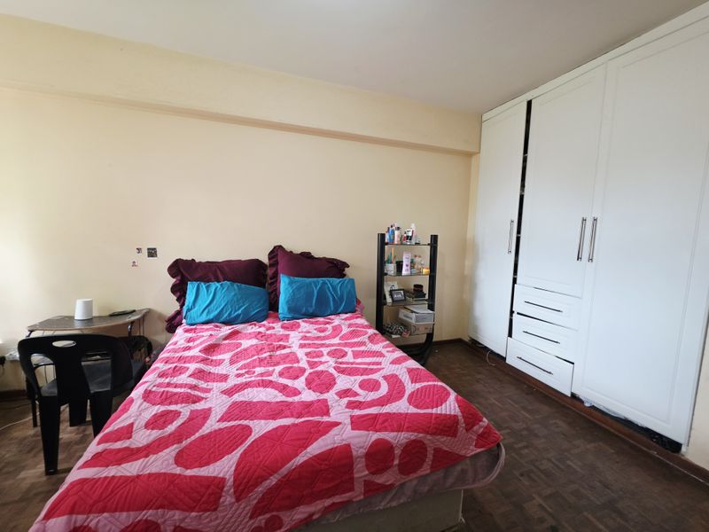 A bedroom featuring parquet flooring and a large white built-in wardrobe with integrated drawers.