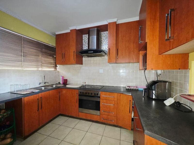A functional kitchen featuring wood-look cabinetry, dark laminate countertops, a built-in oven with extractor fan, and tiled flooring.