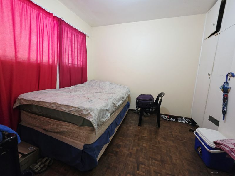 A bedroom featuring parquet flooring and a built-in cupboard, offering a functional space with potential for cosmetic updates.