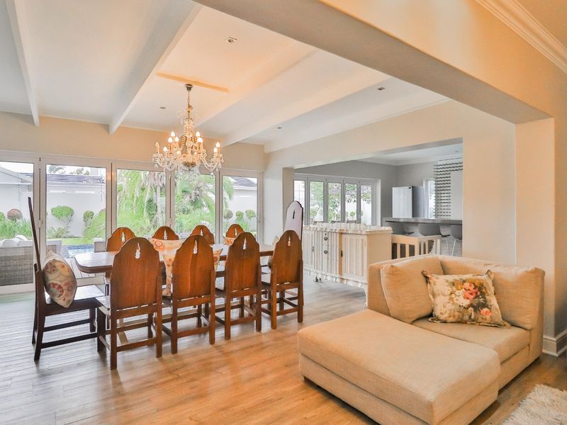 Spacious open-plan living and dining area featuring wood-look flooring, recessed ceilings, and large sliding glass doors opening to the garden.