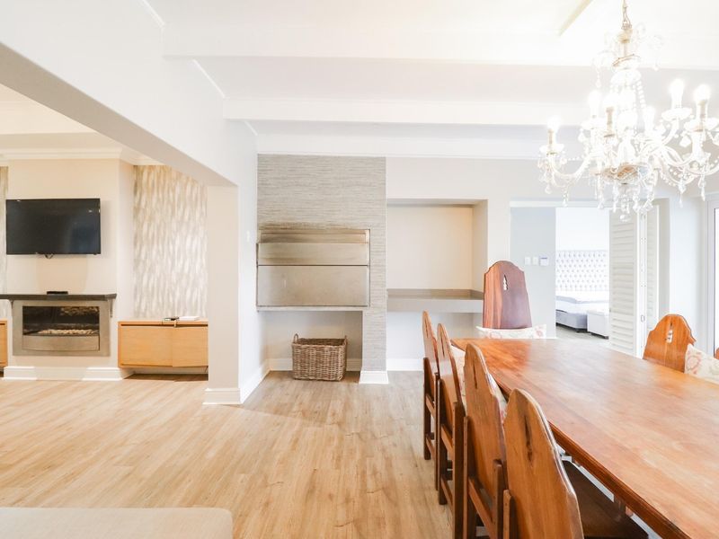 Spacious open-plan living and dining area featuring laminate flooring, a built-in fireplace, and a built-in indoor braai, creating a versatile entertainment space.