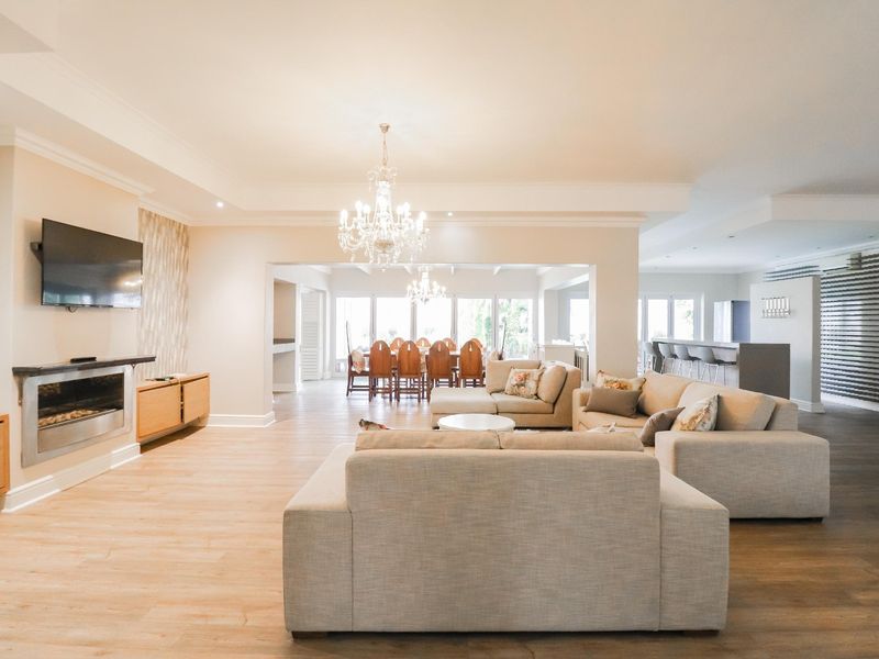 Spacious open-plan living and dining area featuring modern laminate flooring, a built-in fireplace, recessed lighting, and a contemporary kitchen island.