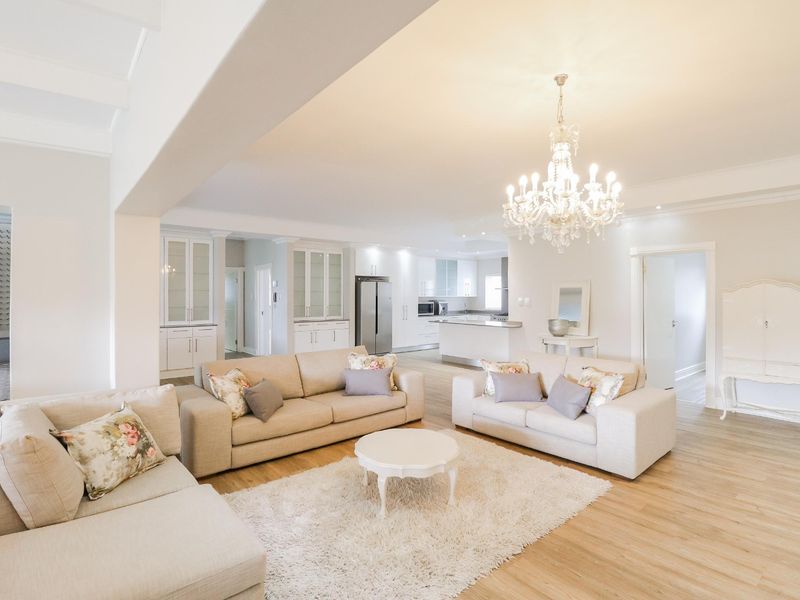 Spacious open-plan living area featuring light laminate flooring, recessed lighting, and a modern kitchen with extensive built-in cabinetry and a central island.