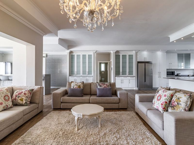 Spacious open-plan living area featuring high-end cabinetry, elegant crown molding, recessed lighting, and seamless flow into a modern kitchen space.