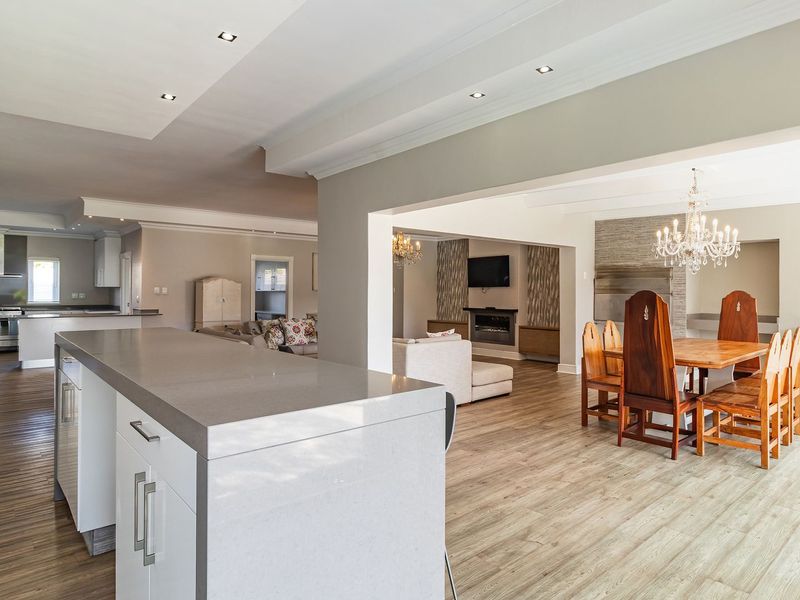 Spacious open-plan living area featuring a modern kitchen with stone island, dining space, and a cozy fireplace, finished with quality laminate flooring.
