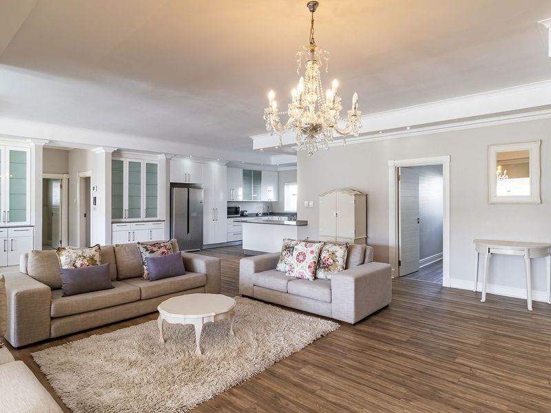 Spacious open-plan living area featuring high-quality laminate flooring, elegant crown molding, recessed lighting, and a seamless transition into a modern, well-appointed kitchen.