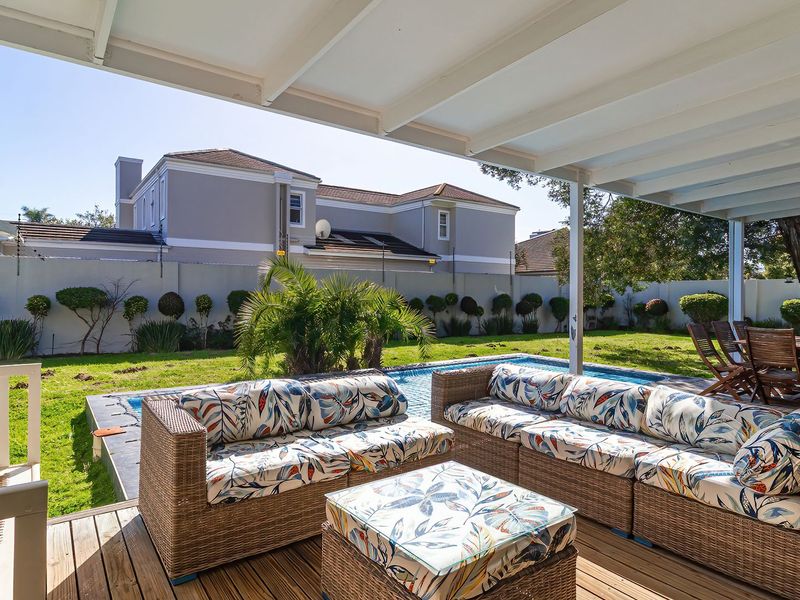 A spacious covered timber deck patio overlooking a private swimming pool and well-maintained garden area, perfect for outdoor entertaining.