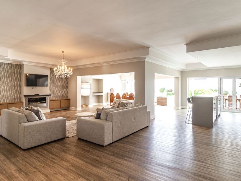 Spacious open-plan living area featuring modern laminate flooring, a built-in fireplace, recessed lighting, and seamless flow to the outdoor patio through sliding glass doors.