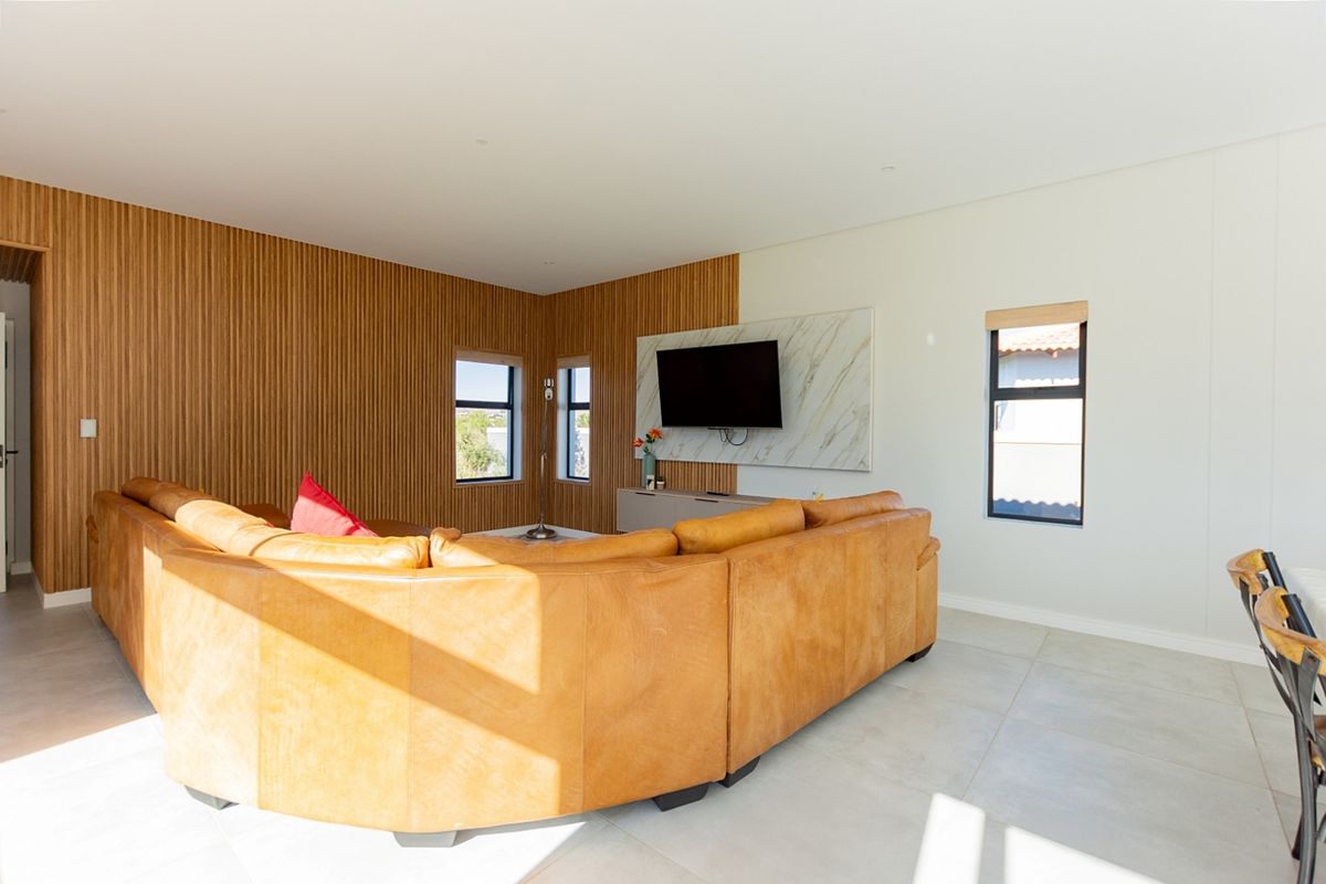 Modern living room featuring stylish timber slat wall paneling, a marble feature wall, and large format floor tiles with abundant natural light.