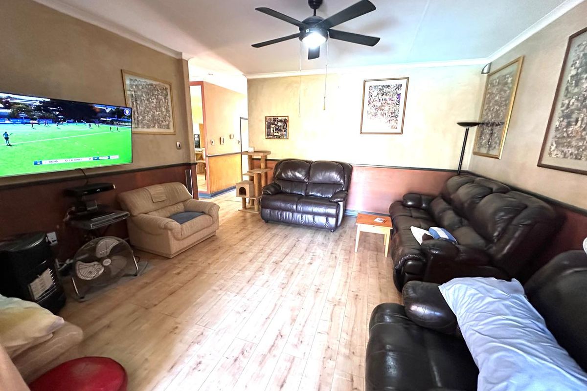 A spacious living room featuring laminate flooring, a ceiling fan, and decorative dado rails, offering a comfortable and functional layout.