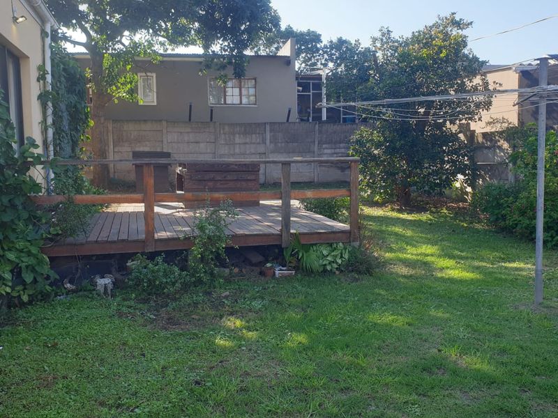 Rear garden area featuring a raised timber deck, lawn space, and perimeter boundary walling.
