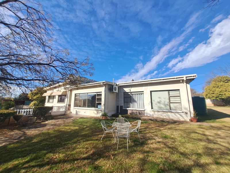 Rear view of the house featuring a paved patio, lawn, solar water heating system, and exterior air conditioning unit.