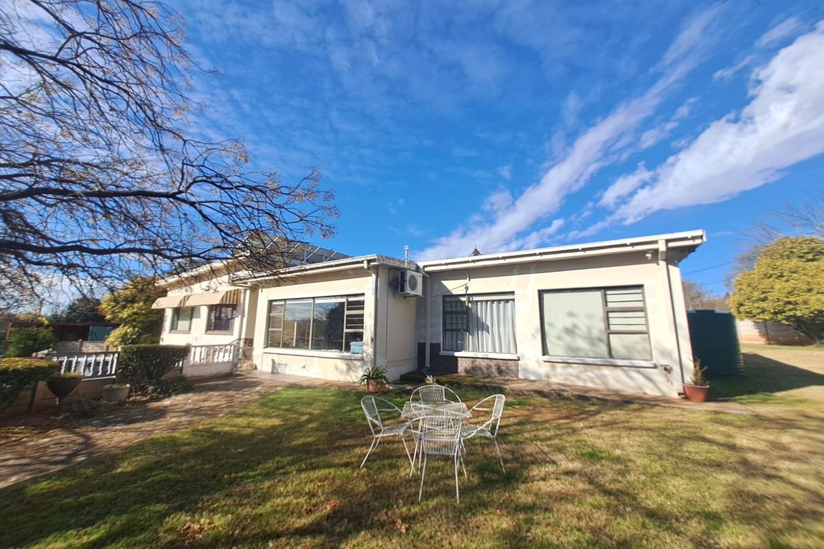 Rear view of the house featuring a paved patio, lawn, solar water heating system, and exterior air conditioning unit.