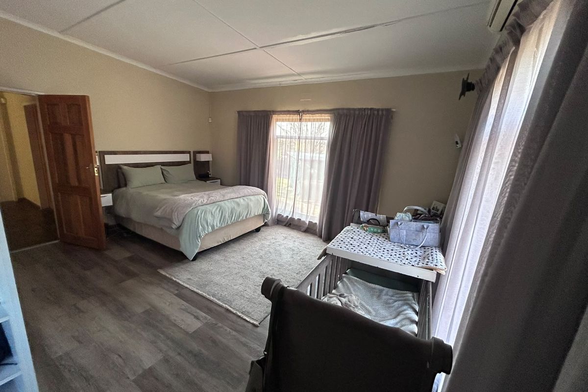 Spacious bedroom featuring laminate flooring, an air conditioning unit, and sliding glass doors providing natural light and access to the exterior.