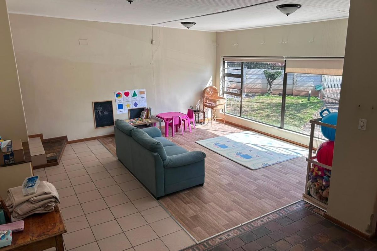 Spacious living area featuring a mix of tiled and laminate flooring, large windows providing natural light, and direct access to the garden.