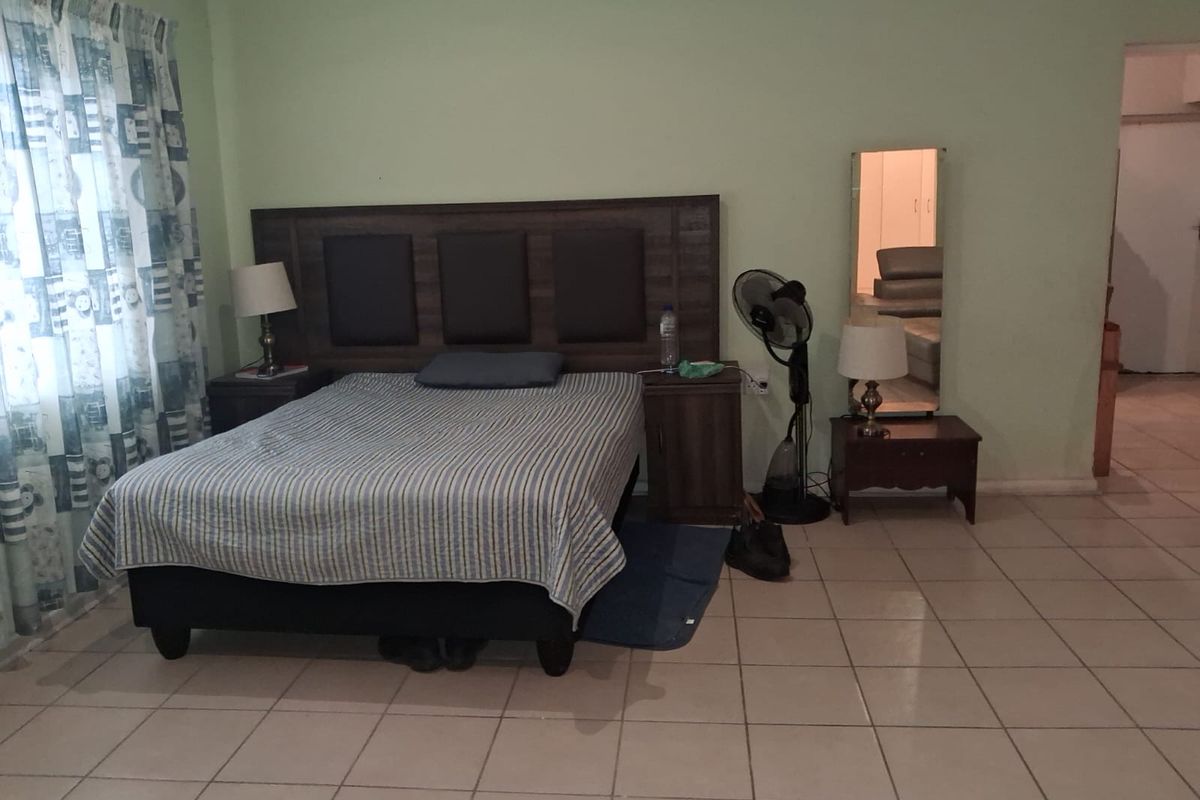 A bedroom featuring tiled flooring and a built-in headboard, requiring cosmetic updates to the wall finishes and general maintenance.