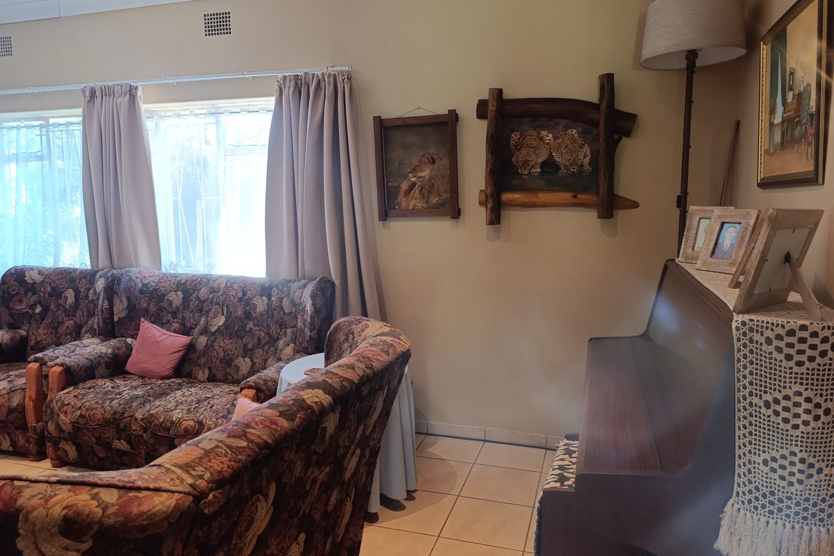 A living room area featuring tiled flooring and ceiling ventilation, providing a functional space with neutral wall tones.