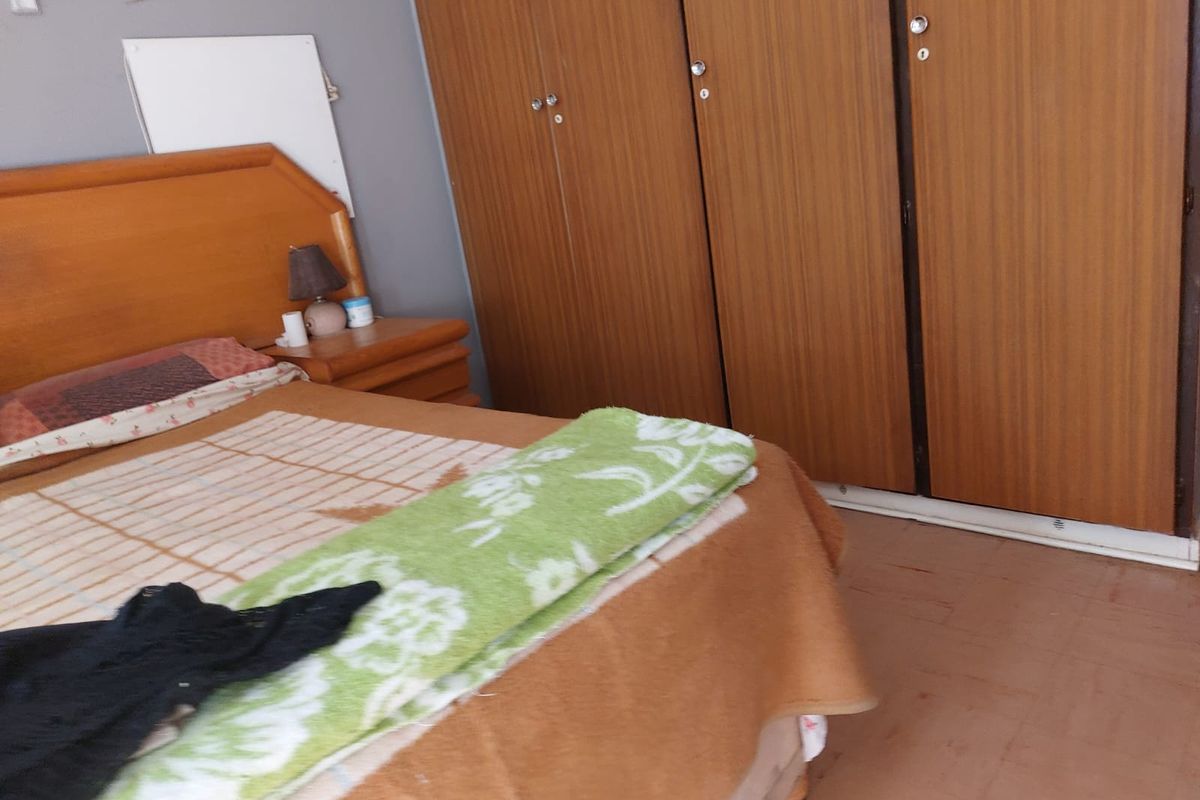 A bedroom featuring built-in wooden wardrobes and tiled flooring.