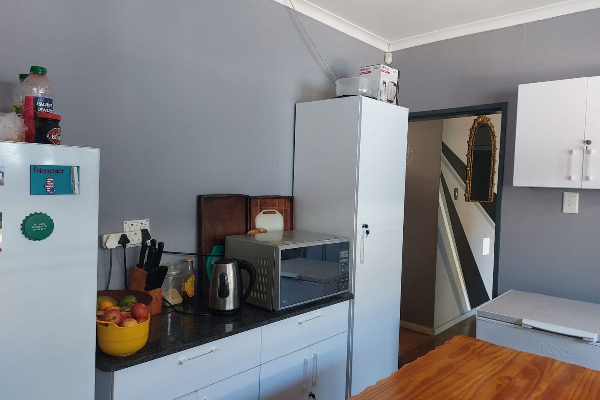 A functional kitchen area featuring white cabinetry, dark granite countertops, and a built-in tall storage unit, providing practical workspace and storage.