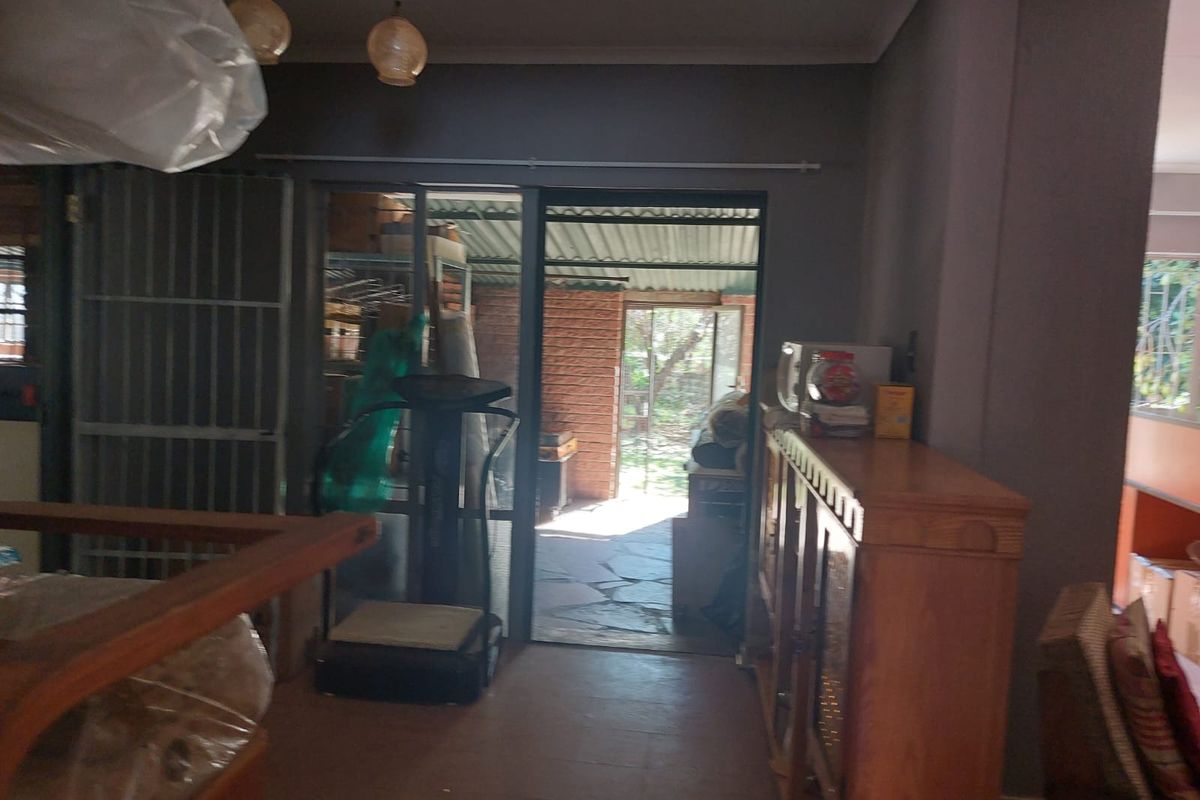 Interior view of a living area featuring sliding glass doors leading to an outdoor patio space with stone paving.