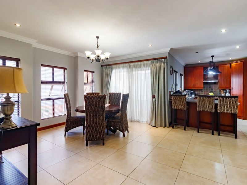 Open-plan living and dining area featuring tiled floors, recessed lighting, and a functional kitchen with wooden cabinetry and a breakfast island.