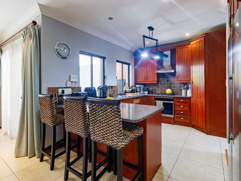 A functional kitchen featuring warm wooden cabinetry, granite countertops, a breakfast bar, and integrated appliances, offering a practical layout for daily cooking and dining.