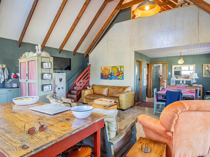 Spacious open-plan living area featuring a vaulted ceiling with exposed timber rafters, a wood-burning stove, and an integrated kitchen space.