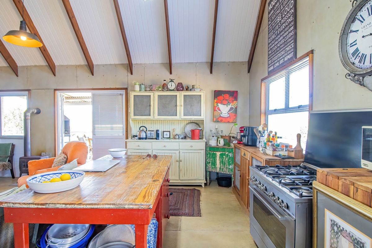Rustic kitchen featuring vaulted ceilings with exposed timber beams, a gas stove, and direct access to an outdoor area through sliding glass doors.