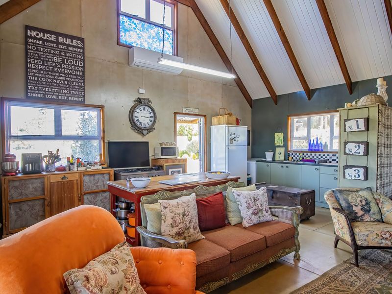 Spacious open-plan living area featuring a vaulted ceiling with exposed timber beams, integrated kitchen cabinetry, and a split-system air conditioner.