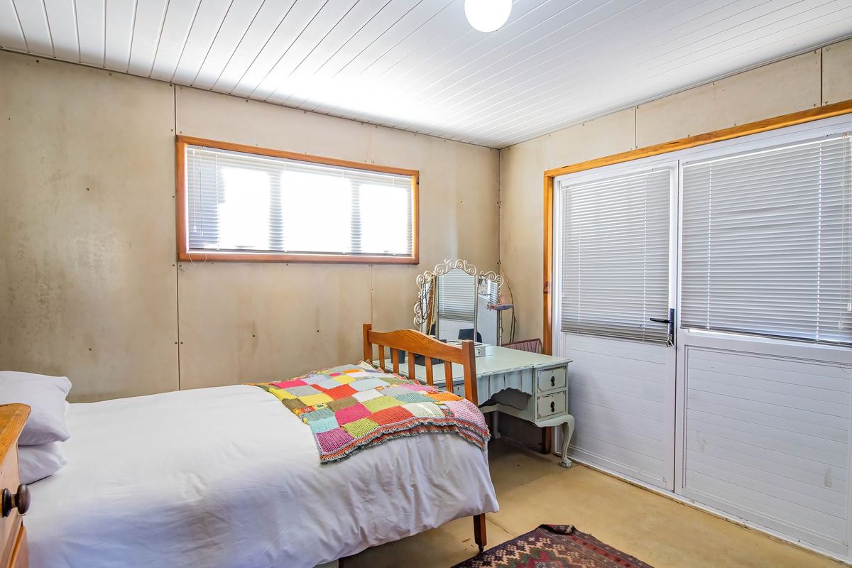 A bedroom featuring panelled walls, a white ceiling, and a sliding glass door providing access to the exterior.