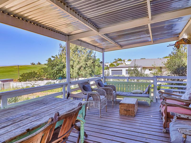 A covered outdoor patio featuring timber decking and a corrugated roof, offering elevated views of the surrounding landscape.