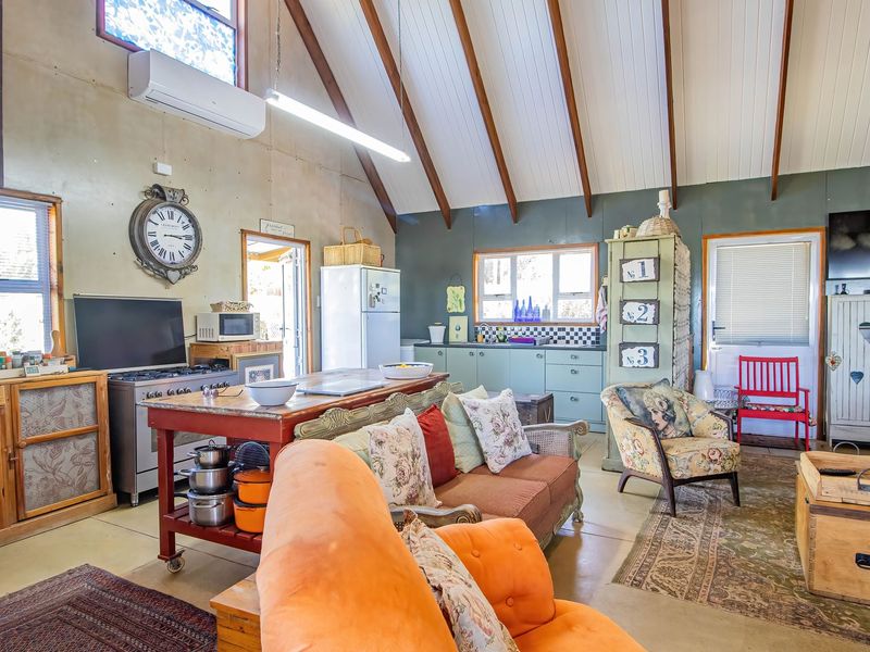 Open-plan living and kitchen area featuring a high vaulted ceiling with exposed timber beams, split-system air conditioning, and a functional kitchen layout.