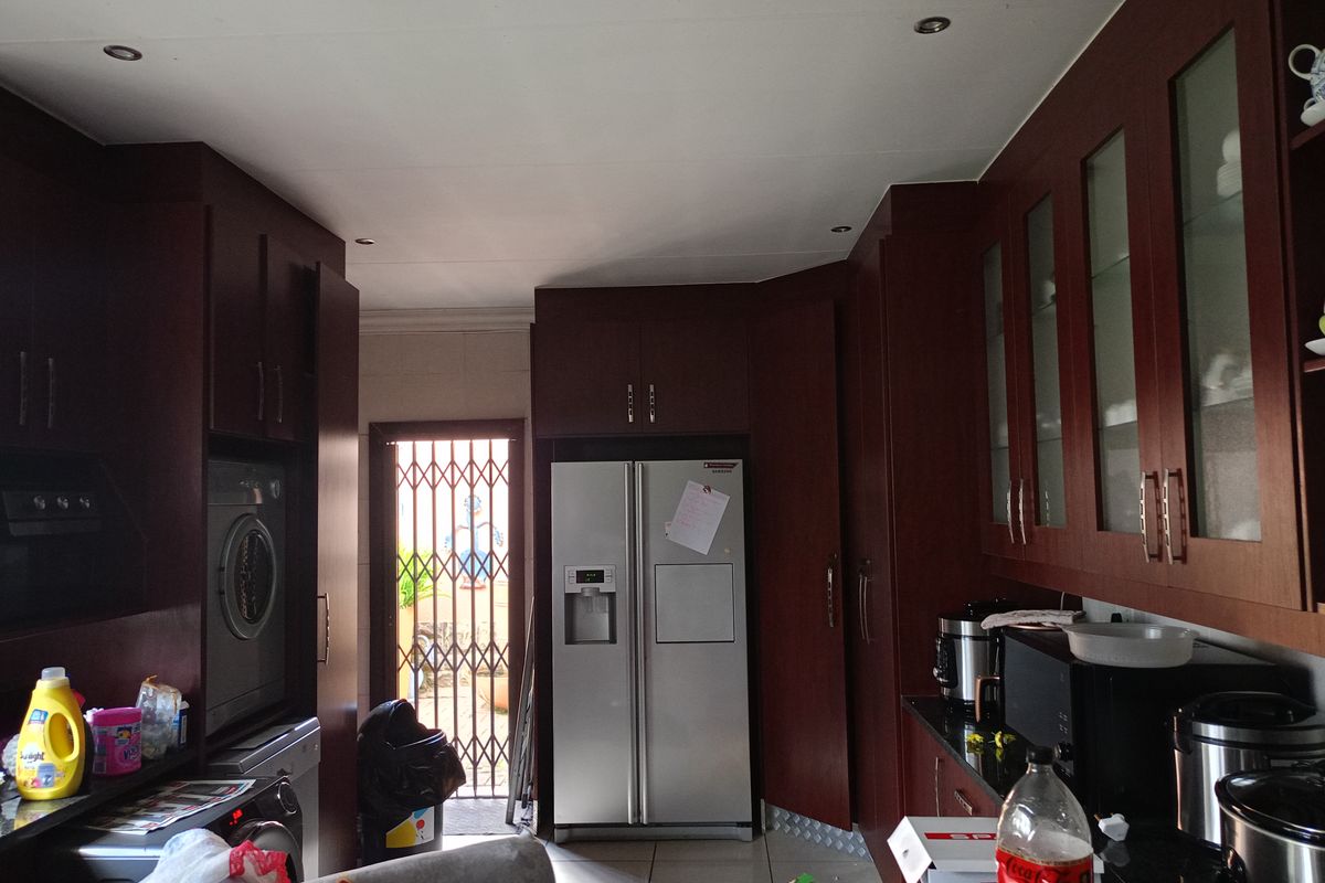 A functional kitchen featuring dark wood cabinetry, granite countertops, recessed lighting, and direct access to an outdoor area via a security gate.