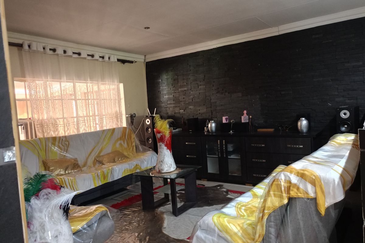 A living room featuring a prominent black stacked stone feature wall, recessed downlighting, and coved ceiling details.