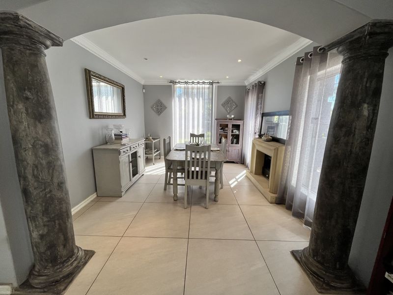 A formal dining room featuring decorative columns, tiled flooring, crown molding, and a built-in fireplace, creating an elegant and defined space.