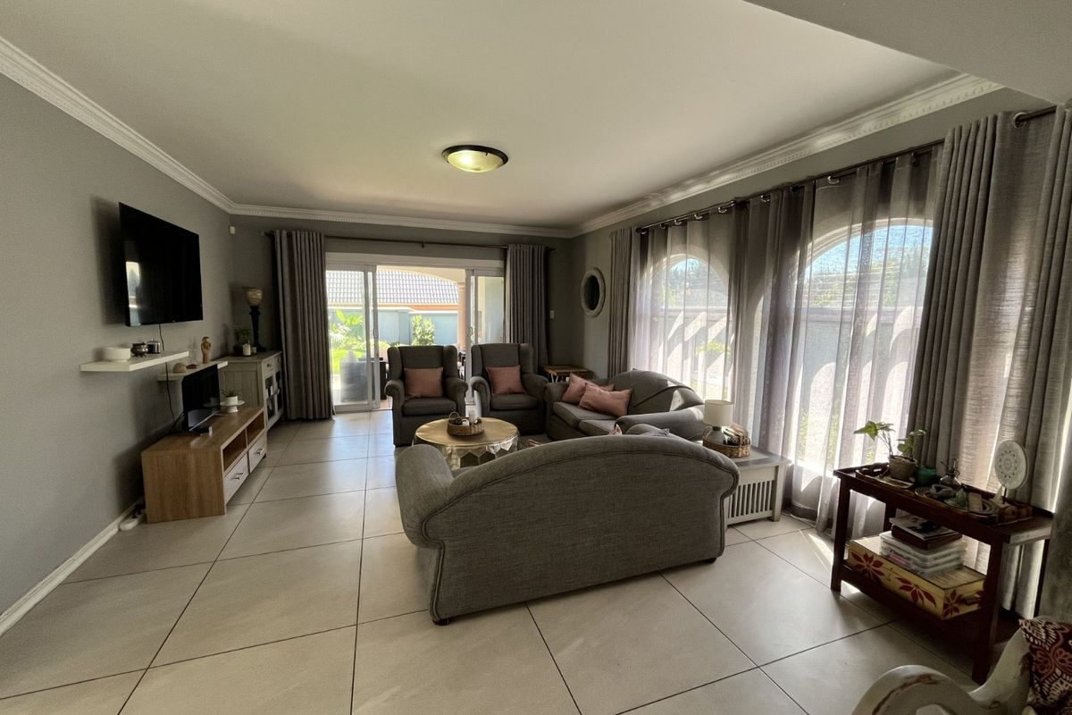 Spacious living room featuring large arched windows, neutral floor tiles, and sliding glass doors providing direct access to the outdoor patio area.