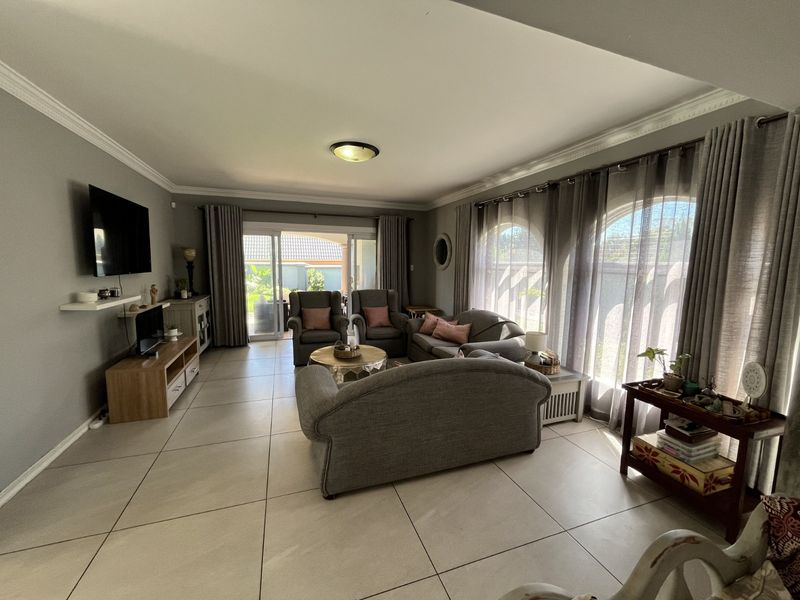 Spacious living room featuring large arched windows, neutral floor tiles, and sliding glass doors providing direct access to the outdoor patio area.