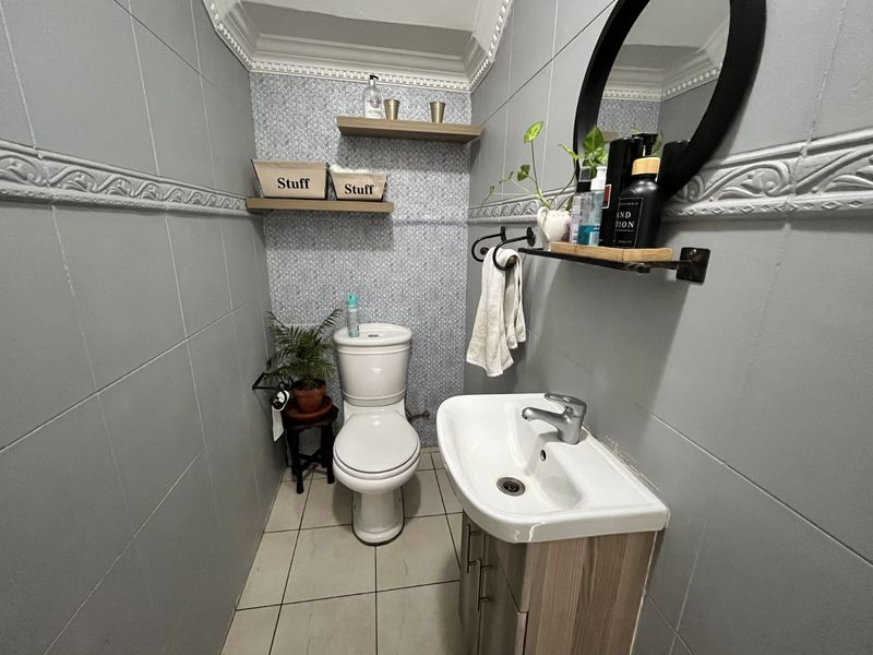 A compact guest bathroom featuring a modern vanity with basin, a standard toilet, and decorative wall tiling with crown molding.