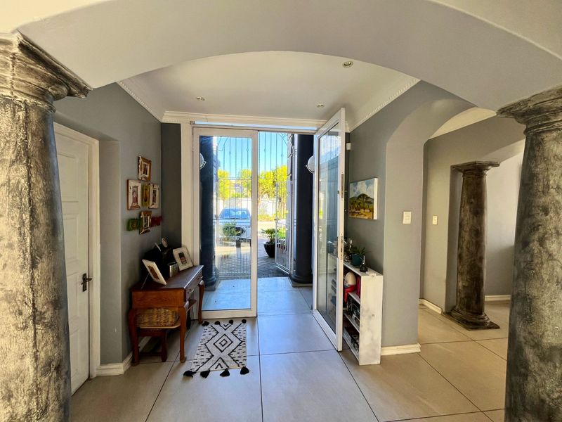 Welcoming entrance hall featuring arched architectural details, decorative columns, and large format floor tiles leading to the front exterior.