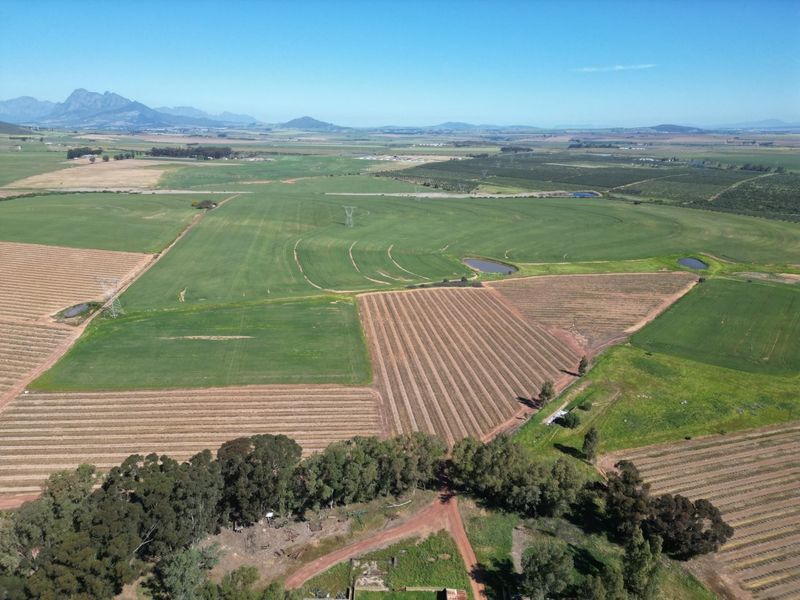 An expansive aerial view of the farm property, showcasing large cultivated fields, irrigation infrastructure, farm dams, and surrounding rural landscape.