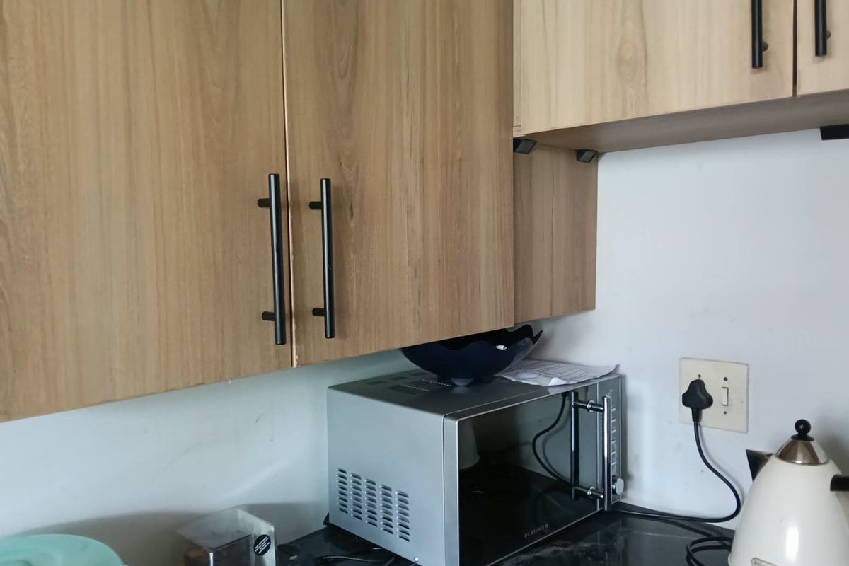 A close-up view of a kitchen workspace featuring modern wood-look cabinetry and a dark stone countertop.