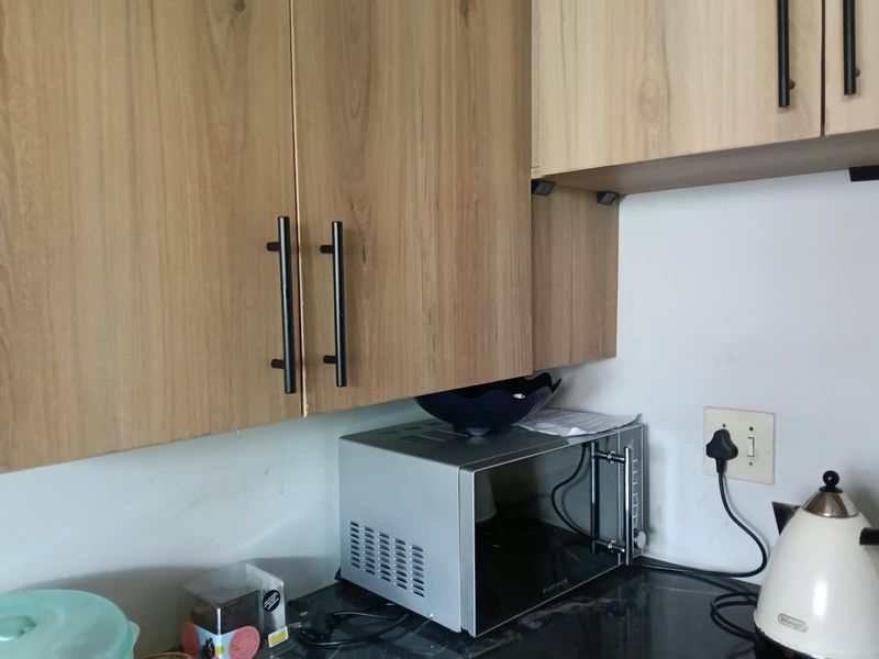 A close-up view of a kitchen workspace featuring modern wood-look cabinetry and a dark stone countertop.