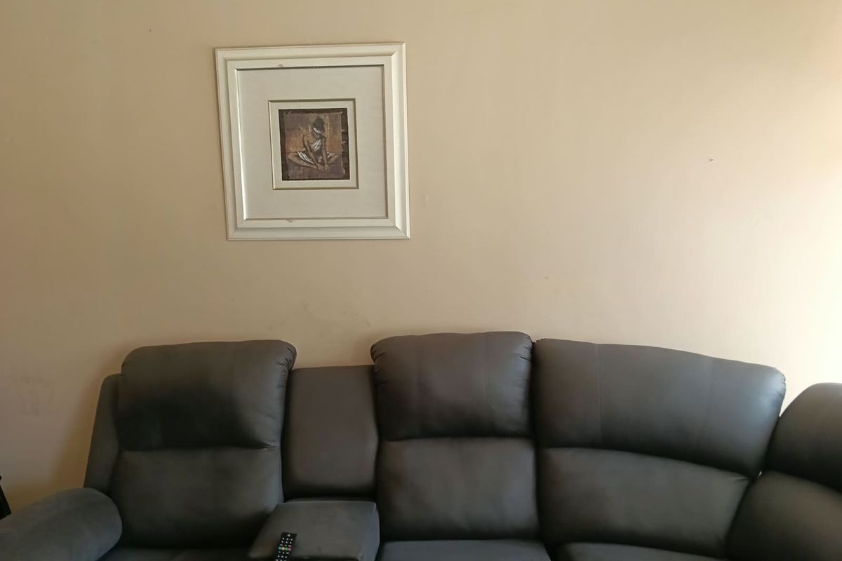 A view of a living room wall featuring neutral paint and a framed artwork.