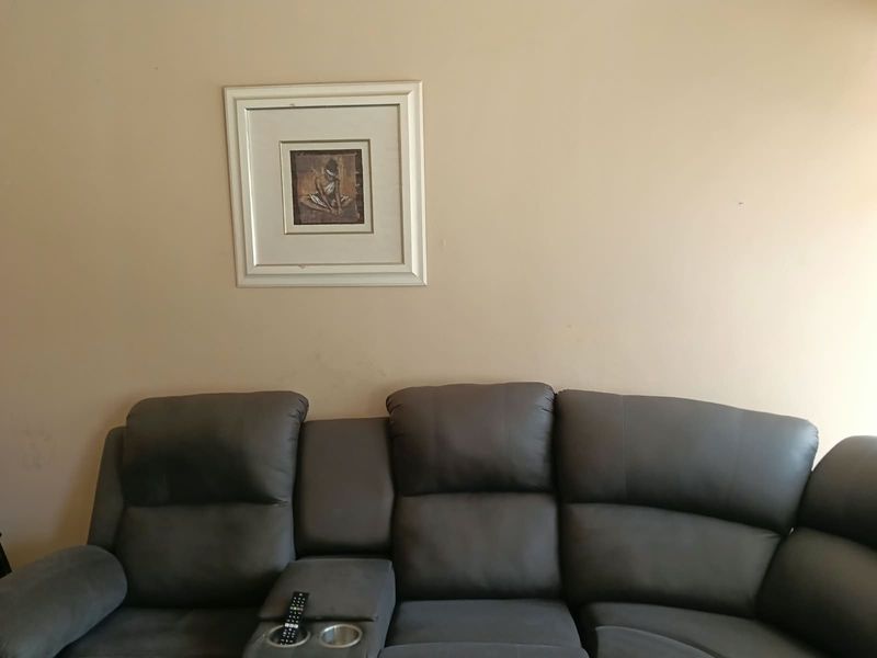 A view of a living room wall featuring neutral paint and a framed artwork.