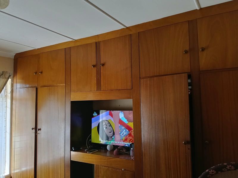 A bedroom featuring extensive floor-to-ceiling built-in wooden cabinetry and wardrobes, providing ample integrated storage space.