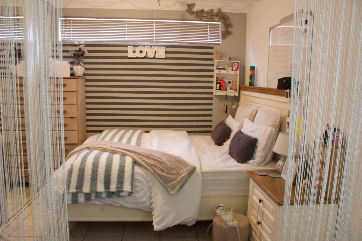 A bedroom featuring tiled flooring and a window with venetian blinds, offering a functional space with neutral wall finishes.